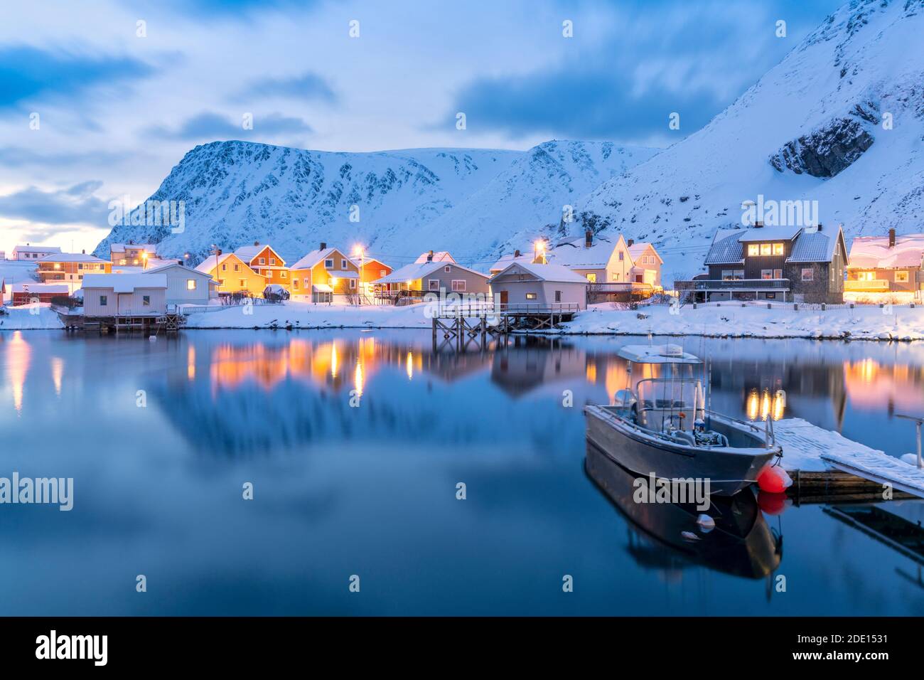 Illuminated village of Sorvaer mirrored in the cold sea during winter dusk, Soroya Island, Troms og Finnmark, Northern Norway, Scandinavia, Europe Stock Photo