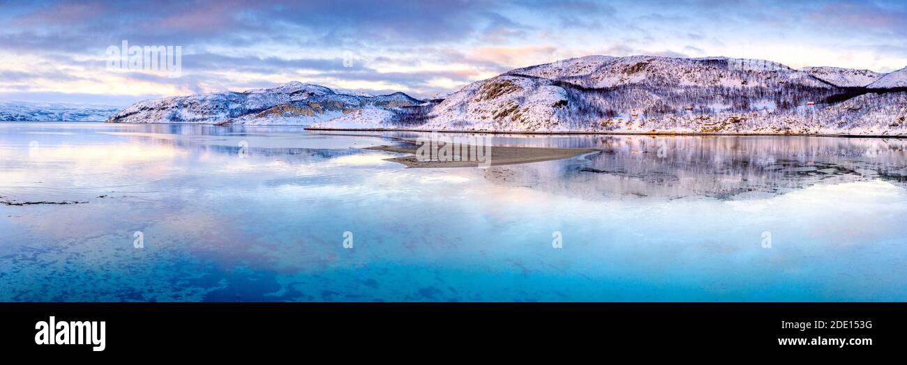Clouds at sunset on snow capped mountains reflected in the clear water of Laksefjorden, Lebesby, Kunes, Troms og Finnmark, Arctic, Norway Stock Photo