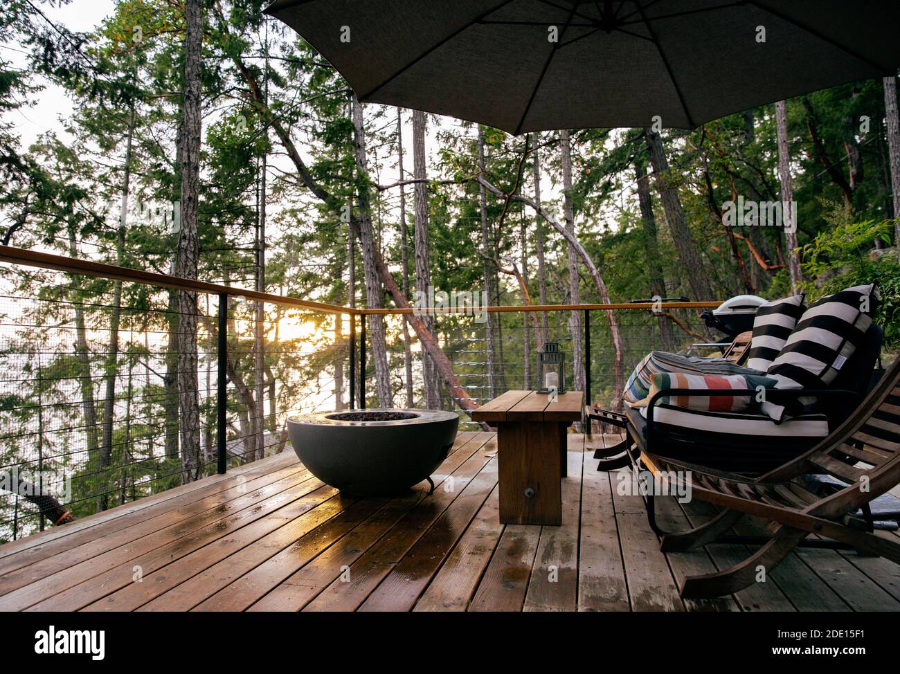 View of the specious deck equipped with gas fire pit and outdoor furniture at sunset after the rain Stock Photo