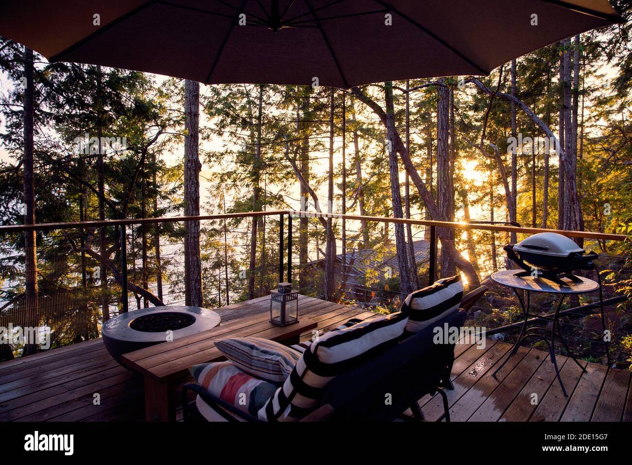 View of the specious deck equipped with gas fire pit and outdoor furniture at sunset after the rain Stock Photo