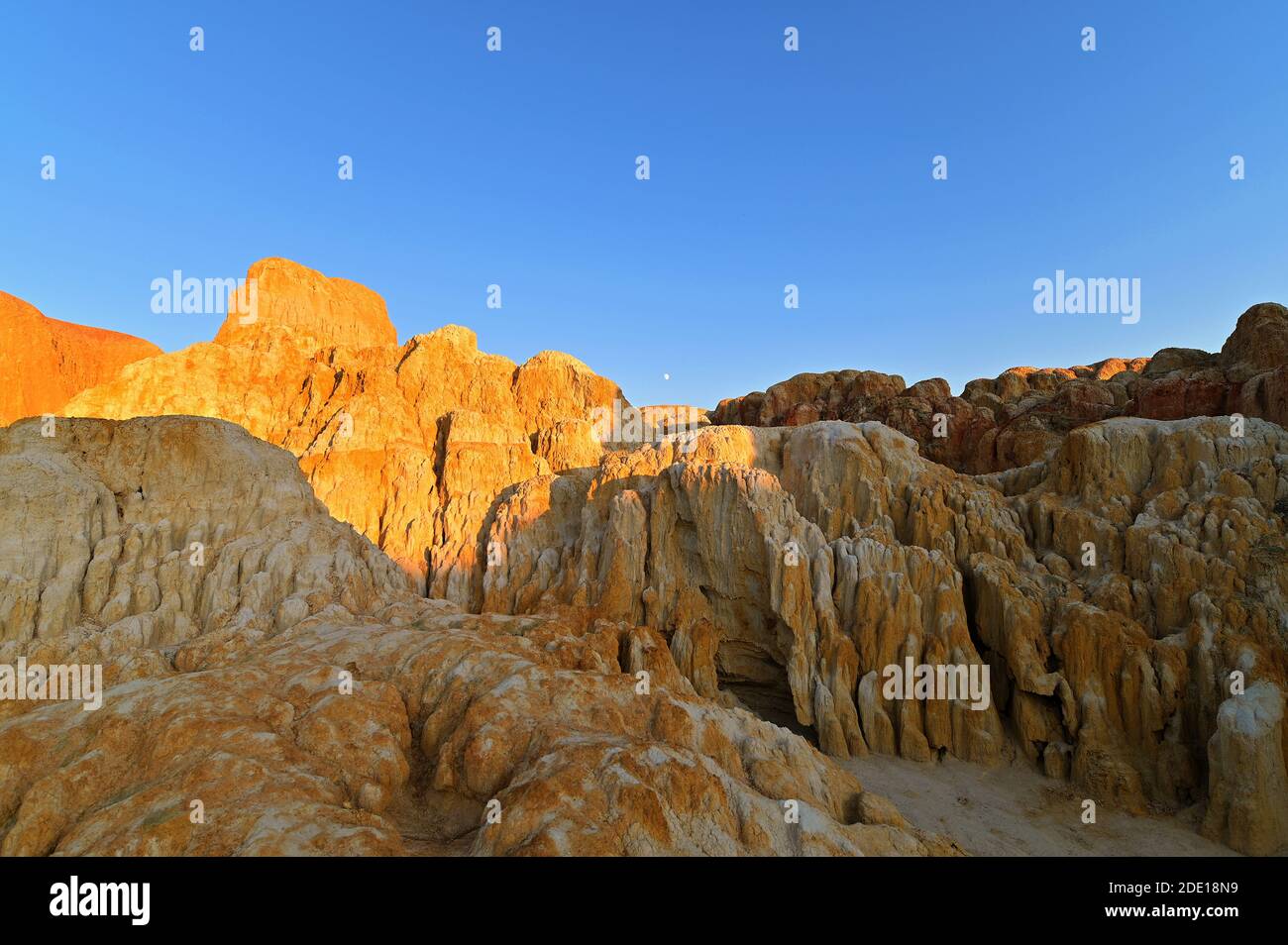 The rising moon at sunset, over the multi-colored eroded rock formations at Wucaitan, Five-Colored Beach, Burqin County, Northern Xinjiang, China Stock Photo