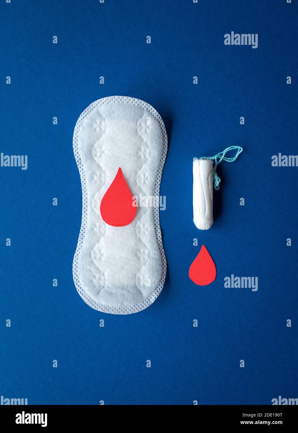 Female menstrual cycle / period products, a tampon and sanitary napkin isolated on blue coloured background Stock Photo