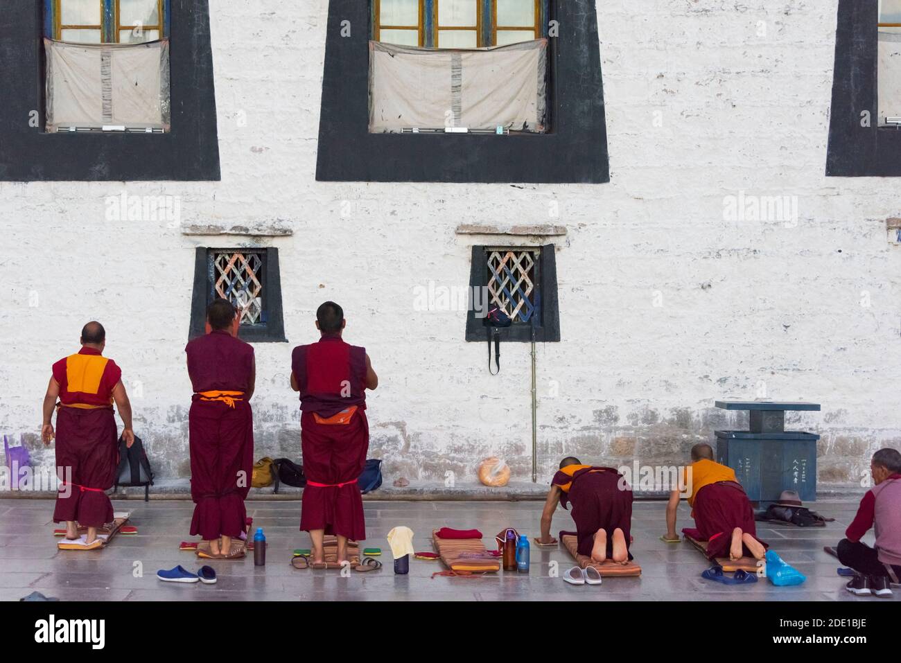 Monks prostrate themselves praying before Jokhang Temple, part of the 'Historic Ensemble of the Potala Palace and a UNESCO World Heritage site, Lhasa, Stock Photo