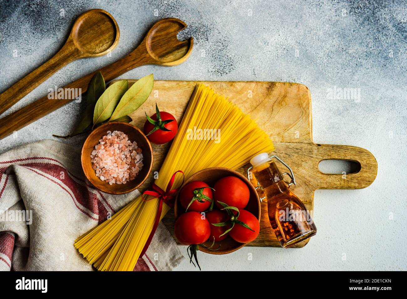 Pasta cooking concept with raw spaghetti and tomato on rustic ...