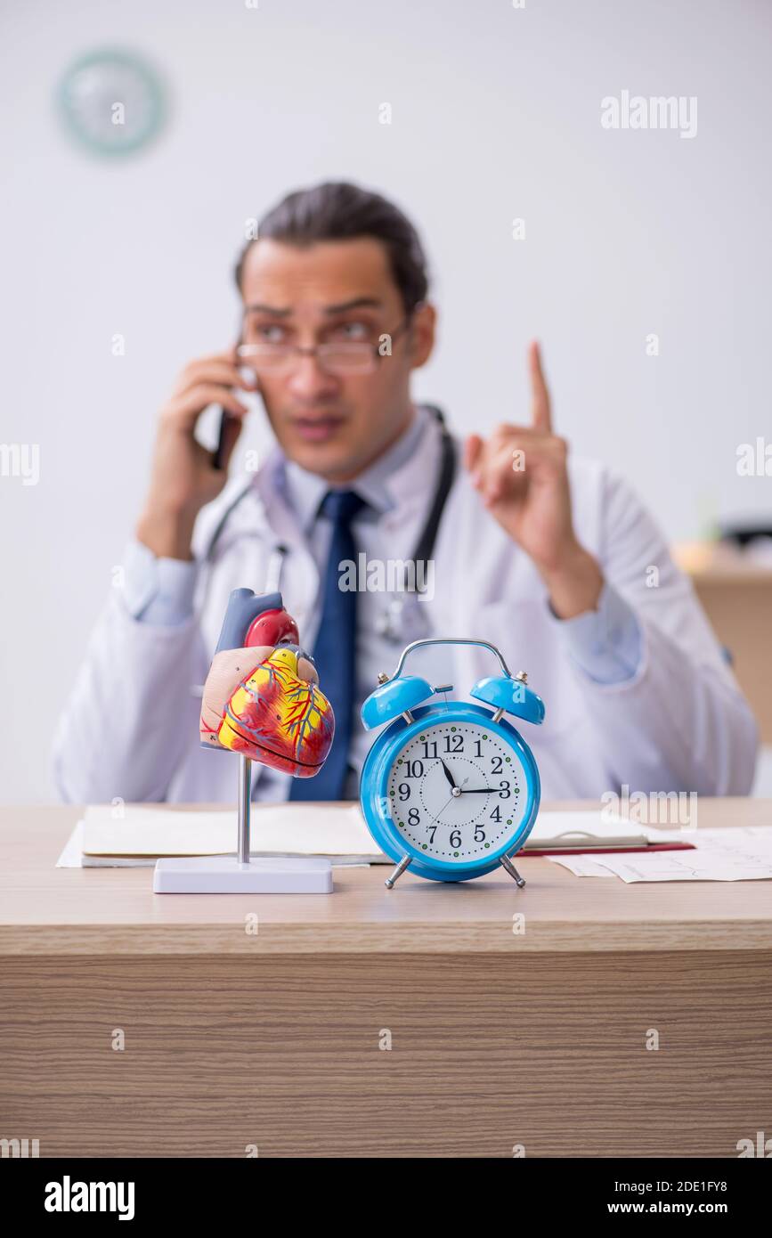 Male doctor cardiologist in time management concept Stock Photo - Alamy