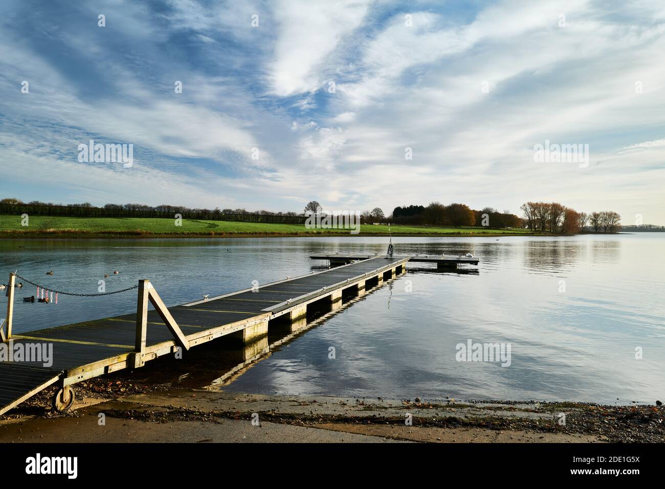 Jetty reaching from the bank of a calm lake on a sunny winter morning. Stock Photo