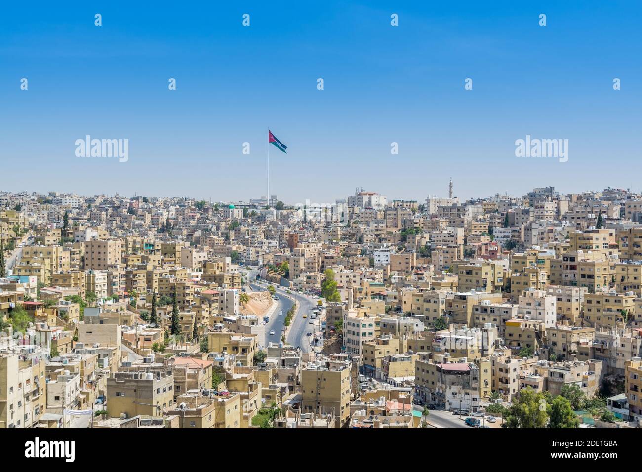 Cityscape of Amman with numerous buildings and Jordanian national flag, the capital and most