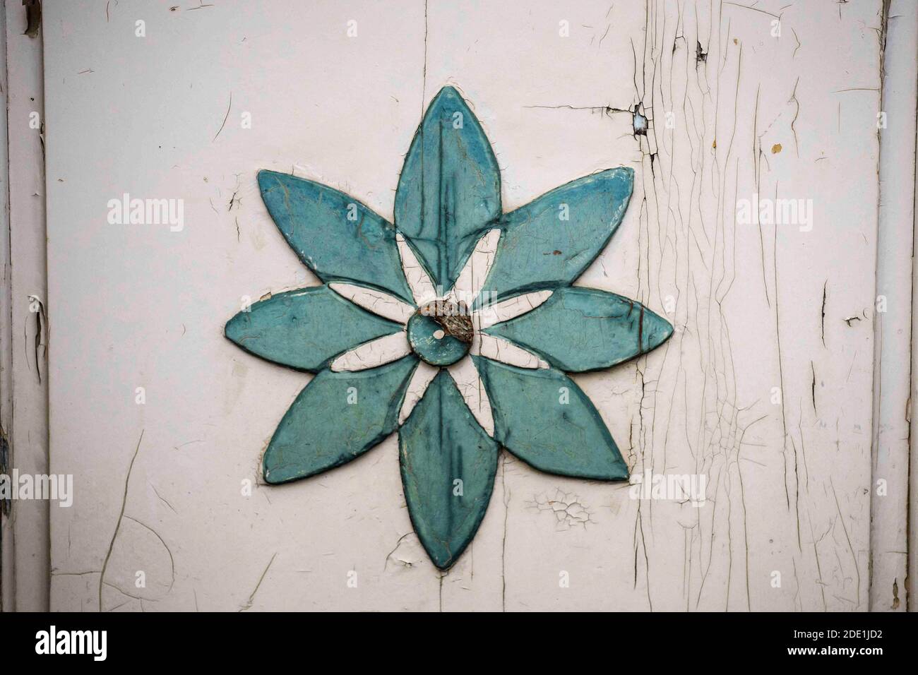 green flower symbol on white wooden wall with flaking paint Stock Photo ...
