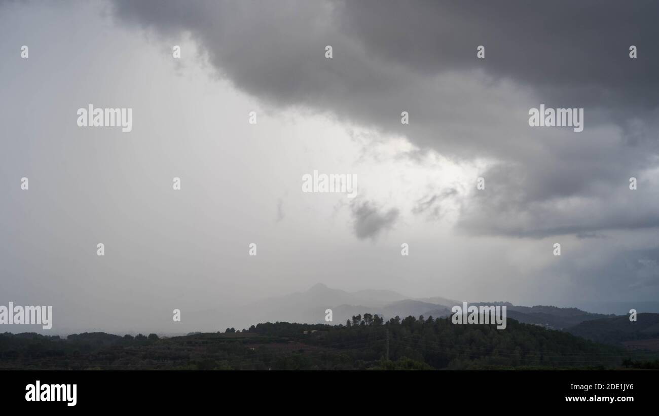 Heavy rainstorm rolling over Spanish countryside with low grey clouds Stock Photo