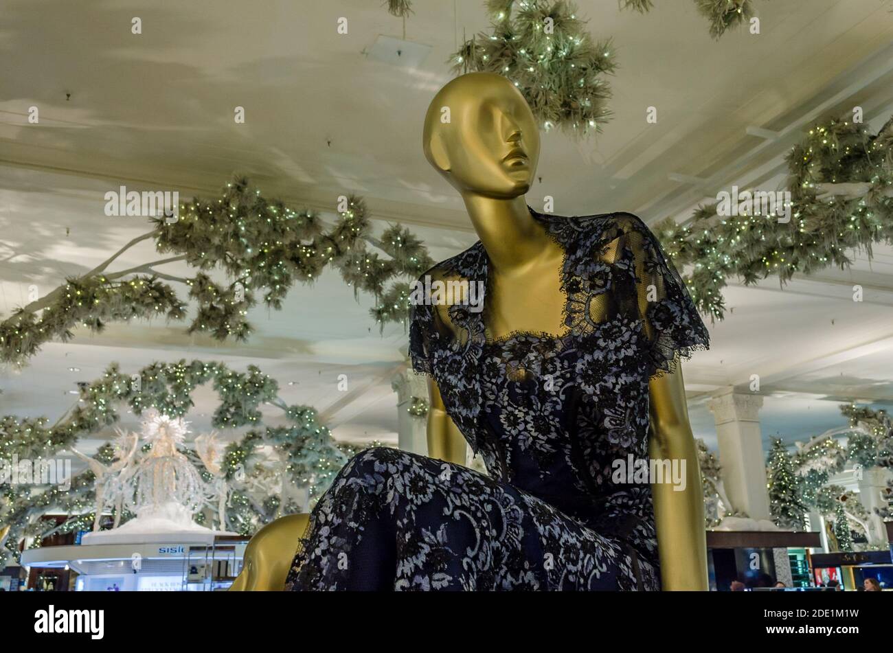 Isolated Woman Mannequin in Deep Blue Dress. Clothes Display Doll inside a Fashion Department Store. Ceiling Chrismas Decoration in Background. Stock Photo