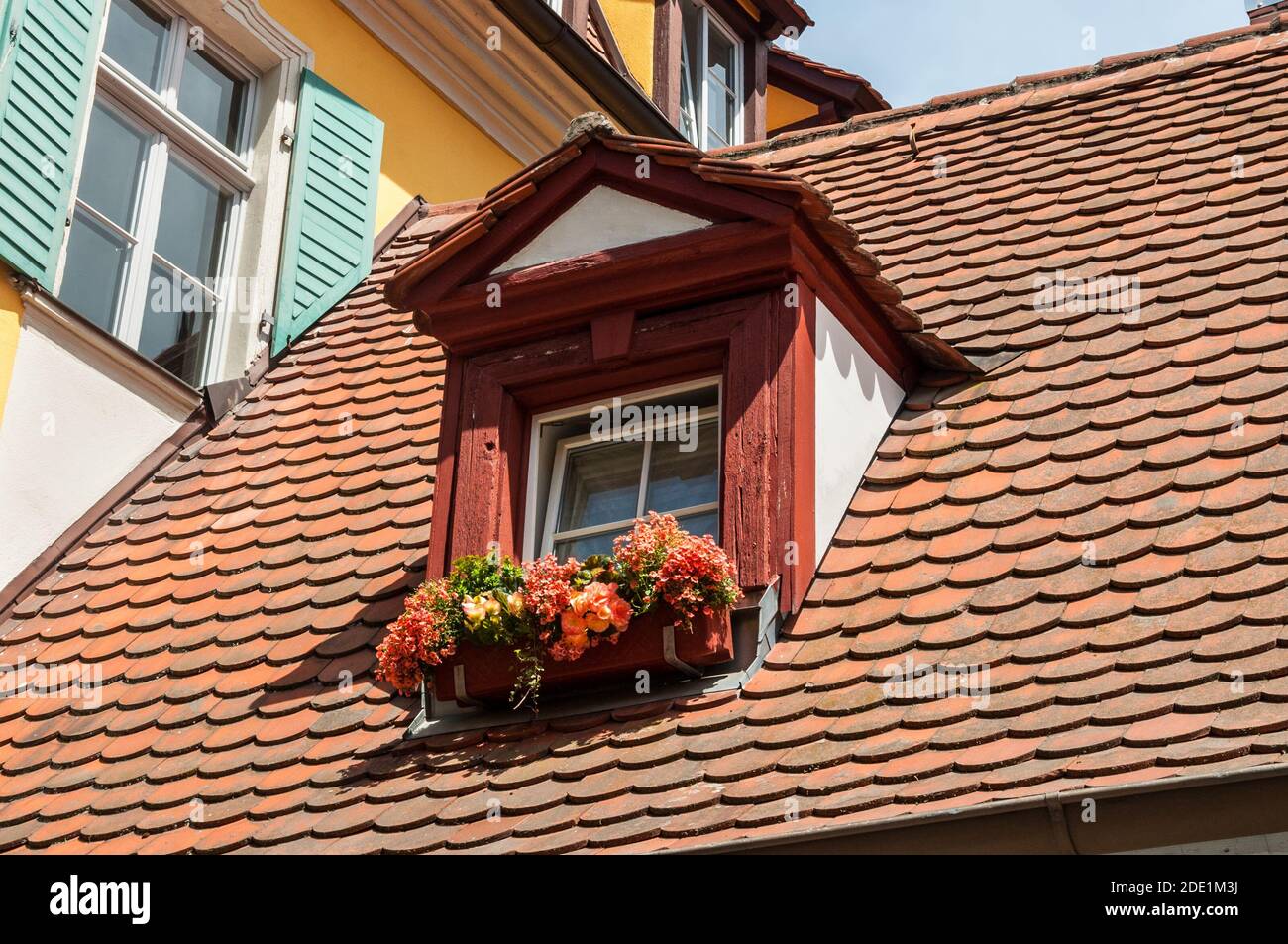 Bamberg, Germany - May 22, 2016: Flowers on mansard roof on traditional half timbered houses in a old town of Bamberg in Germany. Stock Photo