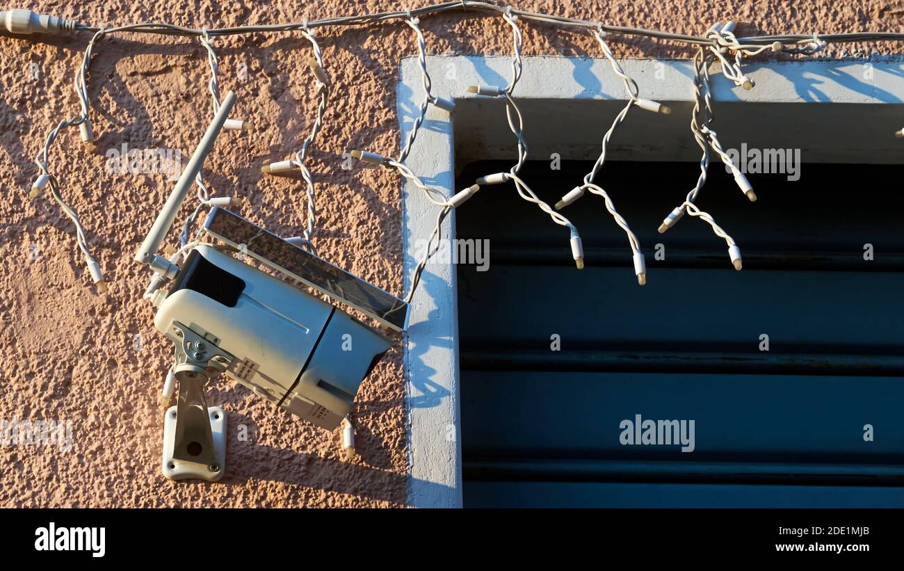 Solar security camera installed on pink wall with Christmas decoration Stock Photo
