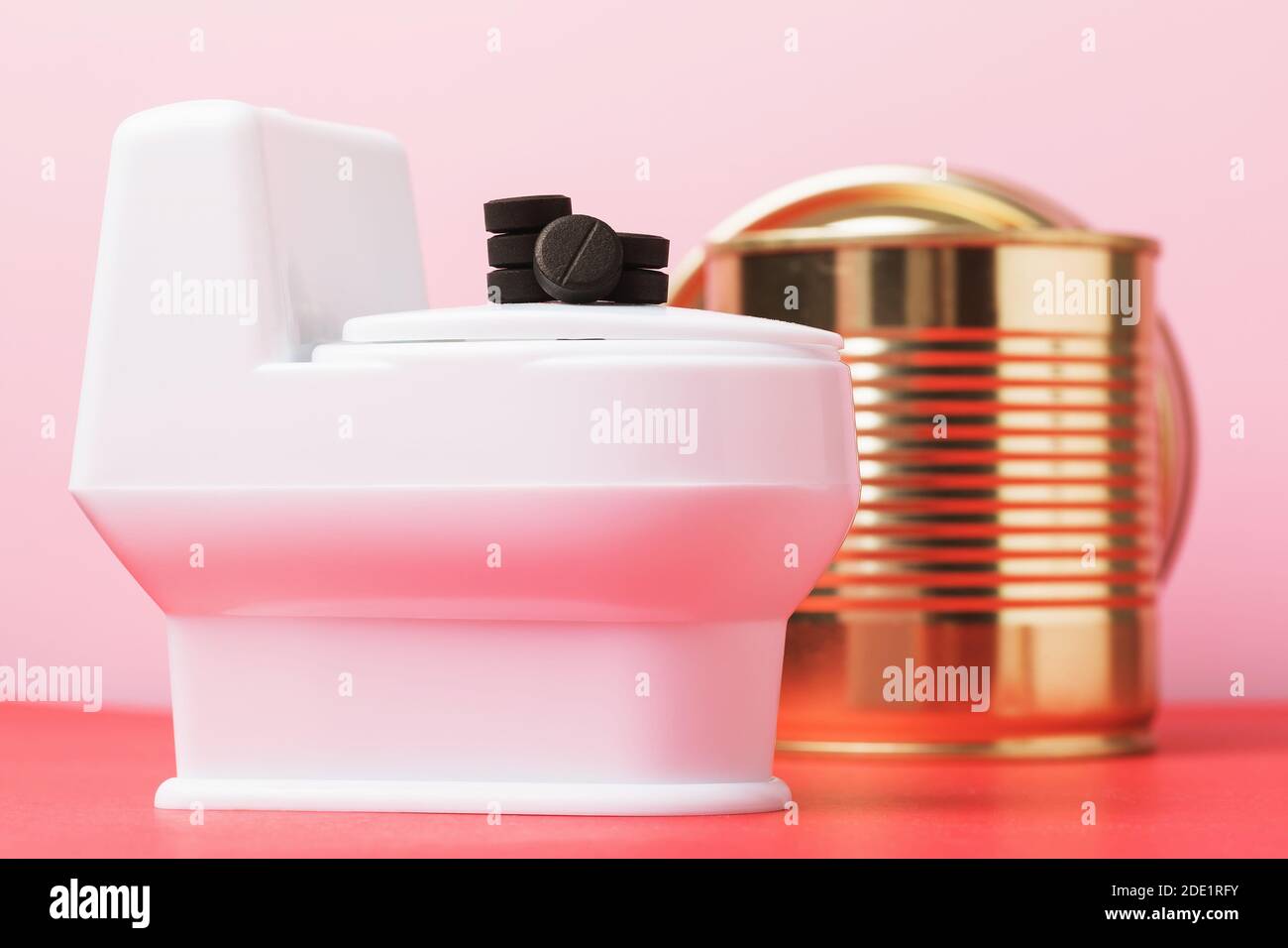 Activated charcoal tablets lie on a toy toilet, closeup. Concept on