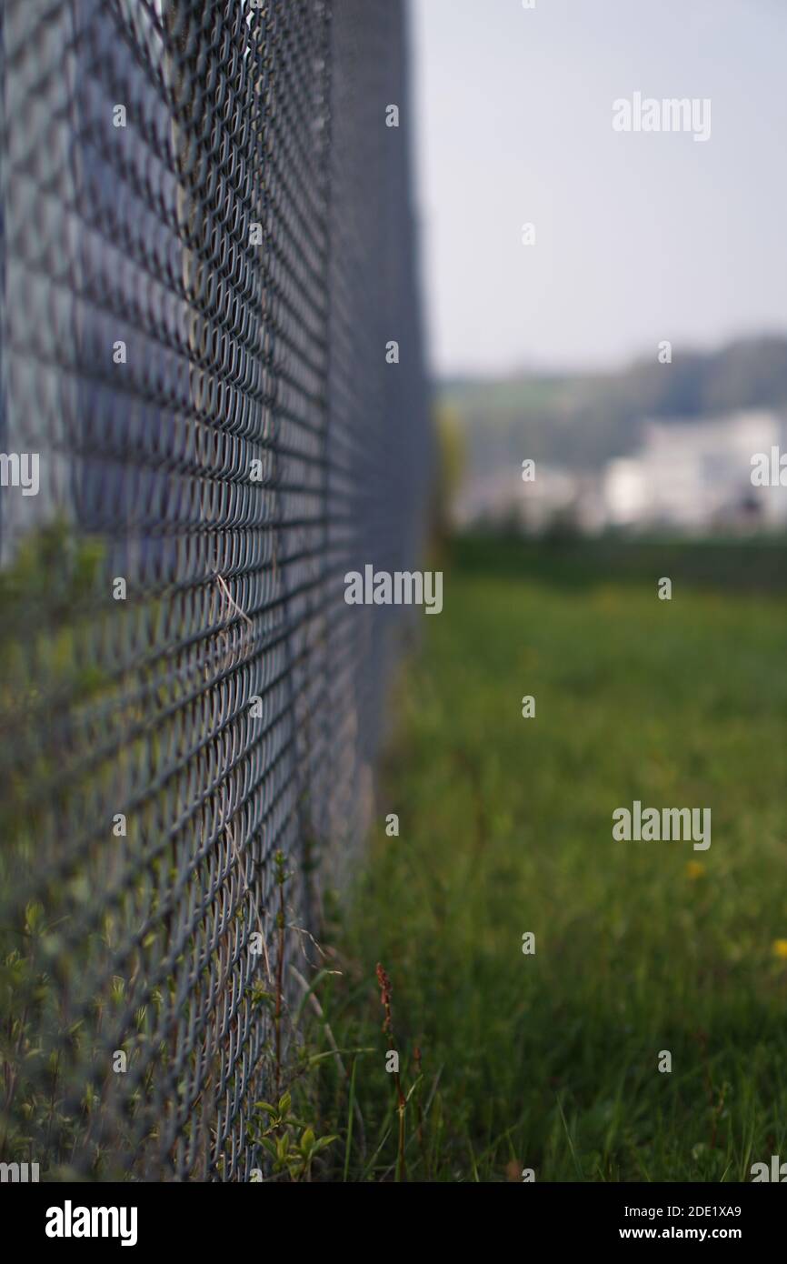 A vertical selective focus shot of a metal fence in the greenery Stock ...