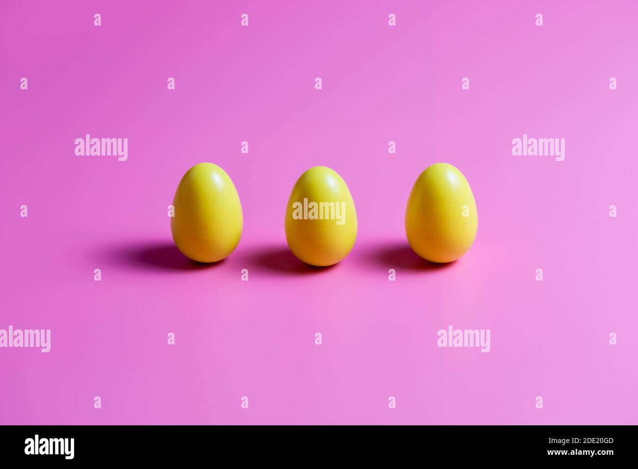 Three Yellow Plastic Easter Eggs on pink background. Stock Photo