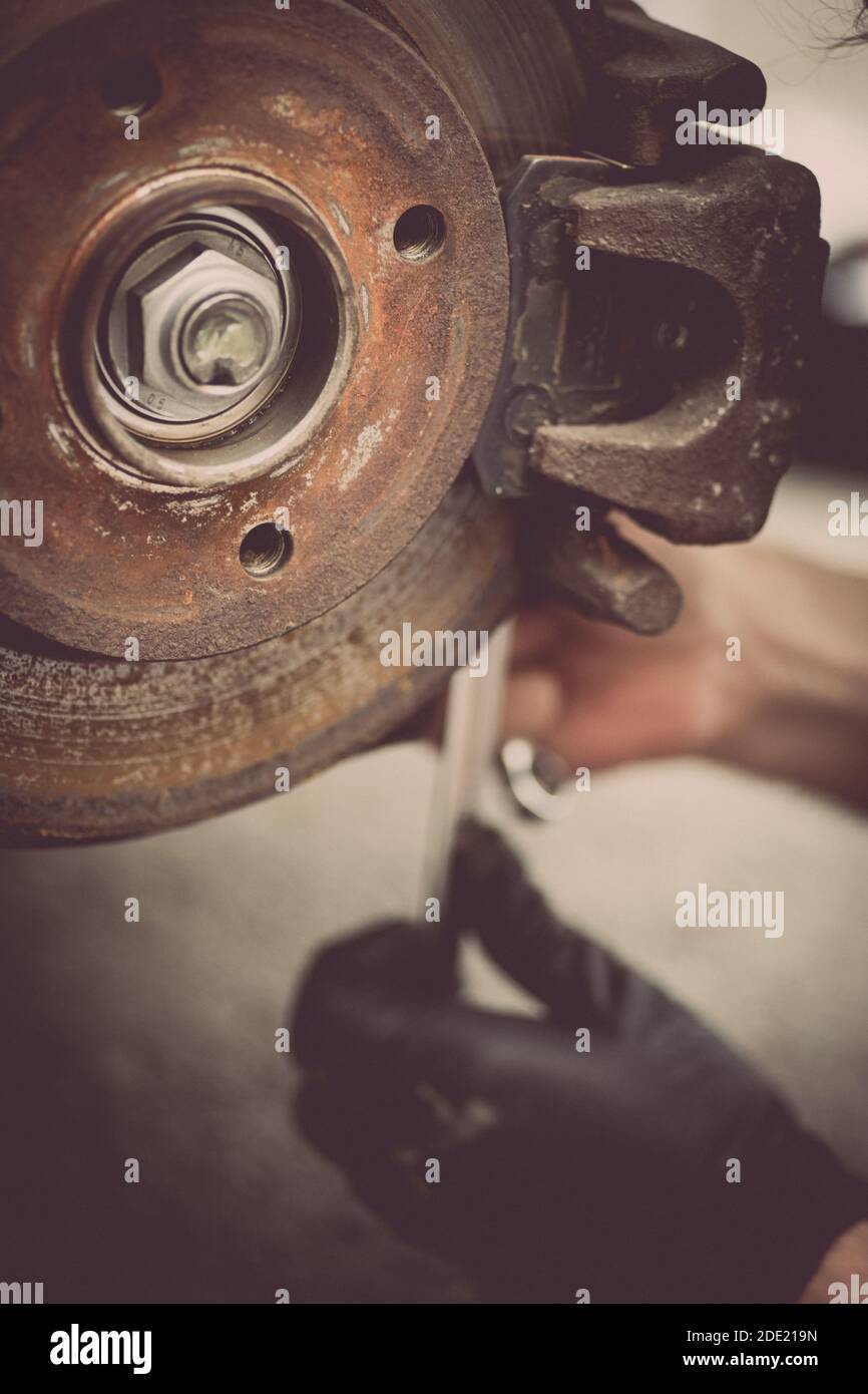 Close up shot of a mechanic working at a car worn and rusty brake disk