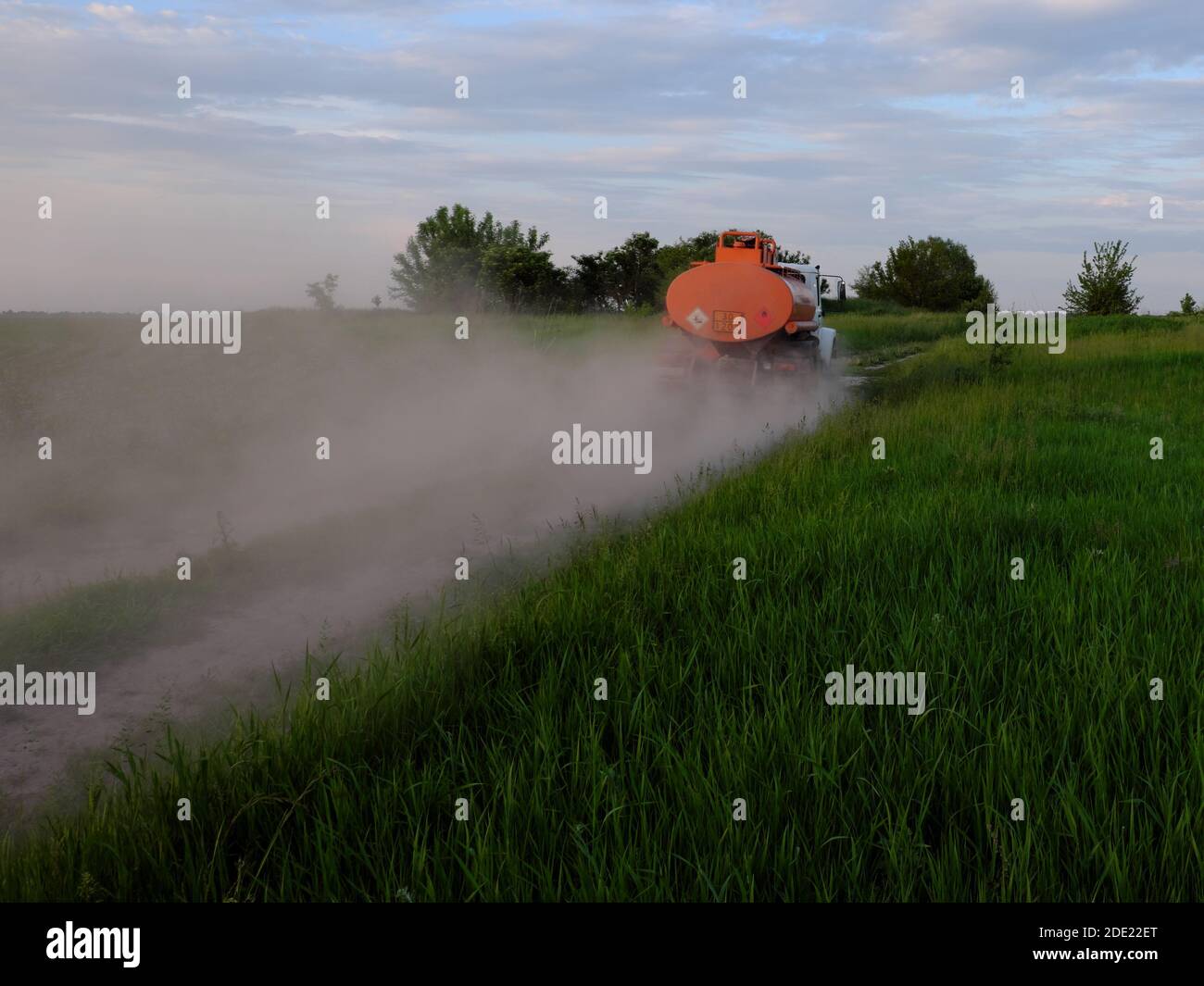 A fuel truck rushing along a dirt road leaving behind clouds of dust. Stock Photo