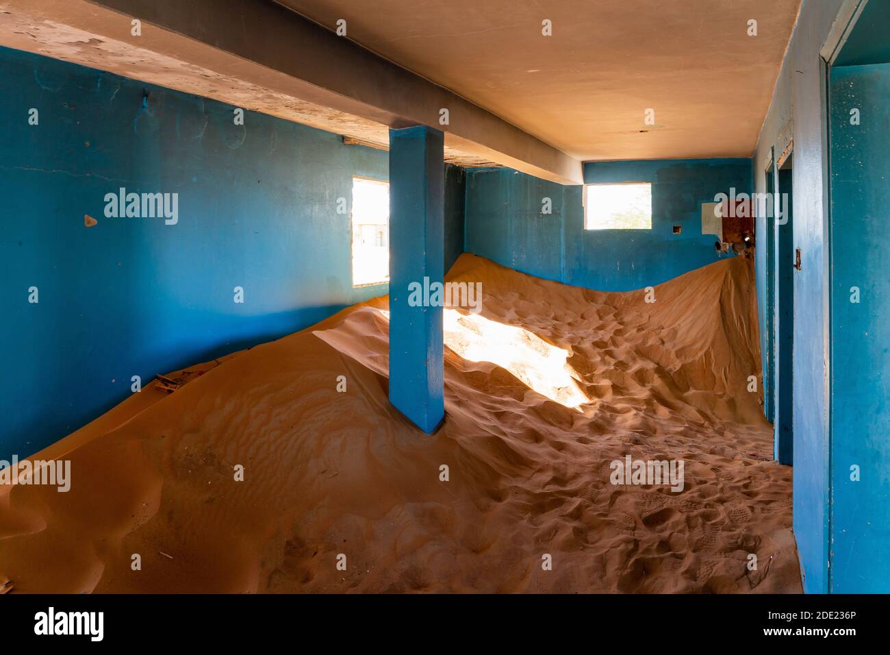 Neglected house interior with blue walls buried in the sand in Al Madam
