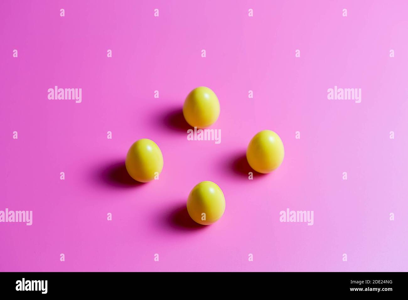 Four Yellow Plastic Easter Eggs on pink background. Stock Photo