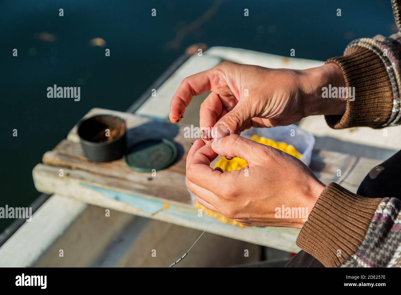 Close up of hands setting worm as bait on fishing hook. Man is holding