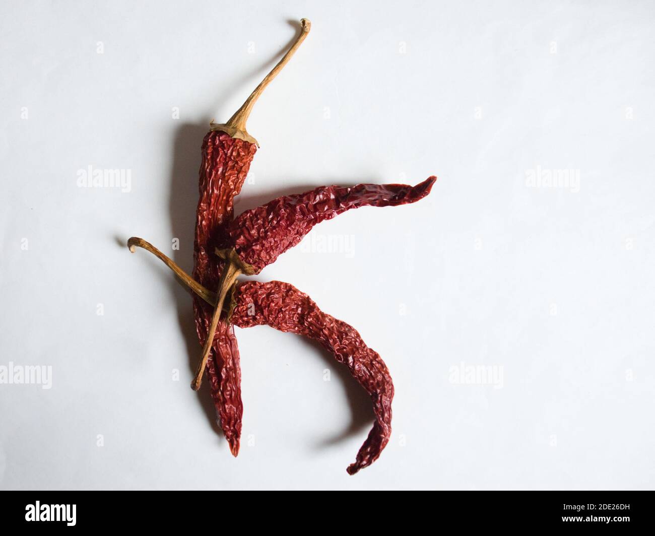 Letter K lined with red peppers on a white background. Symbol in the form of the letter K. Pepper lined in the letter K on a white background. Stock Photo