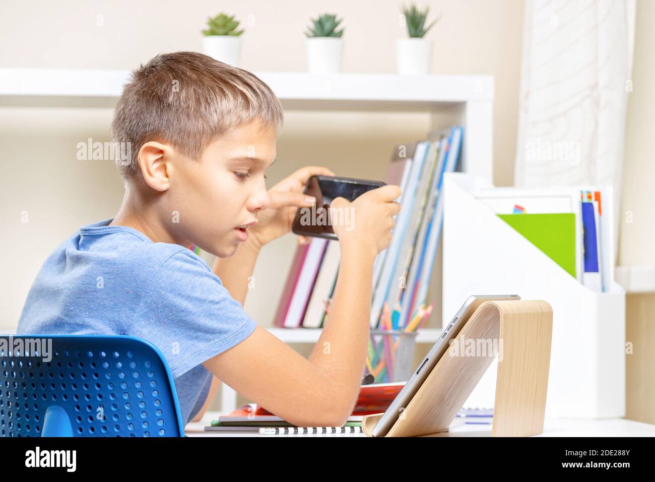 Teen boy distracting from online lesson and playing video games, scrolling  phone. Learning difficulties, online education, entertainment at home Stock  Photo - Alamy