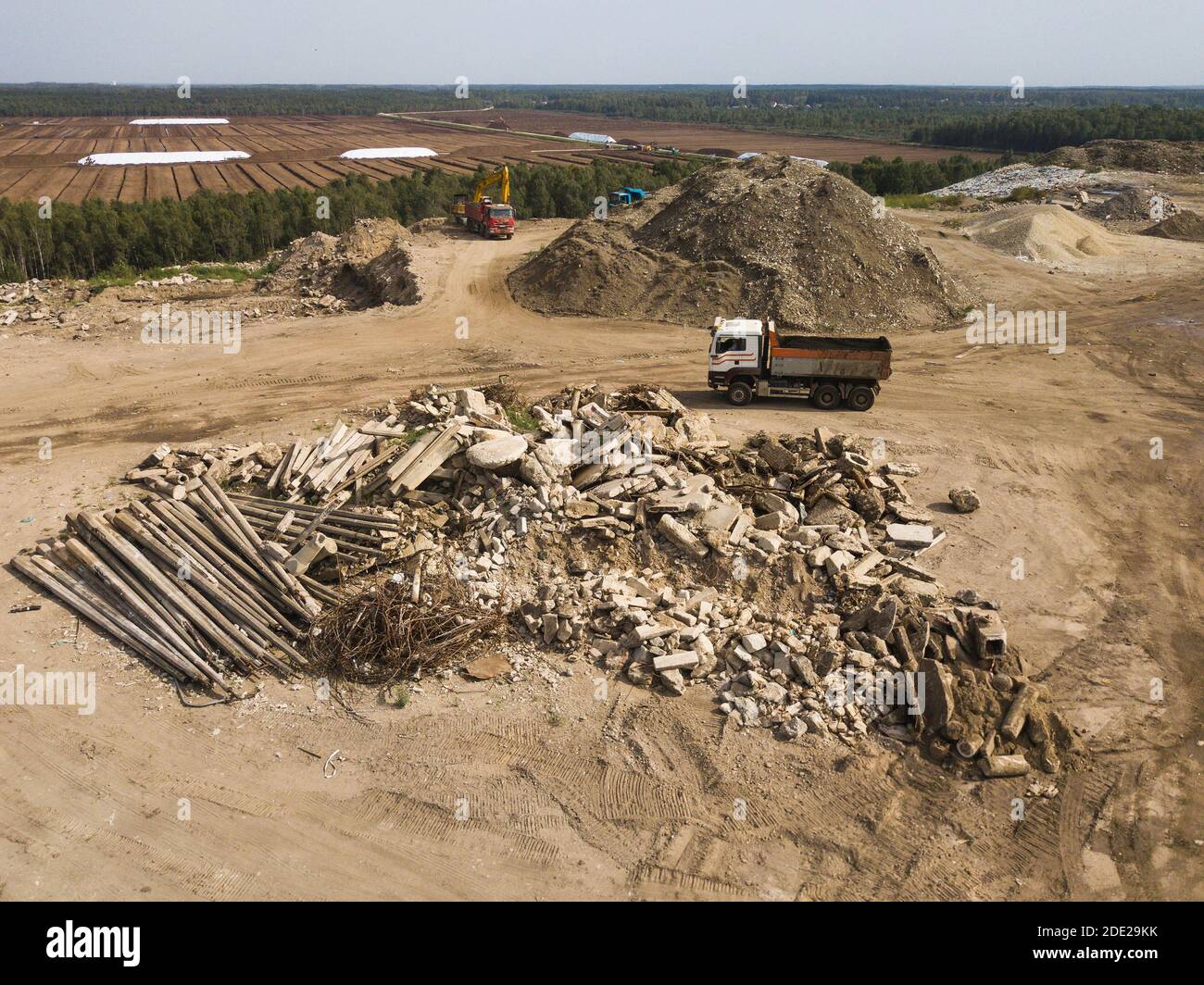 Aerial view of truck near heap of waste on construction site. Fragments of concrete, wire, and rocks. Stock Photo