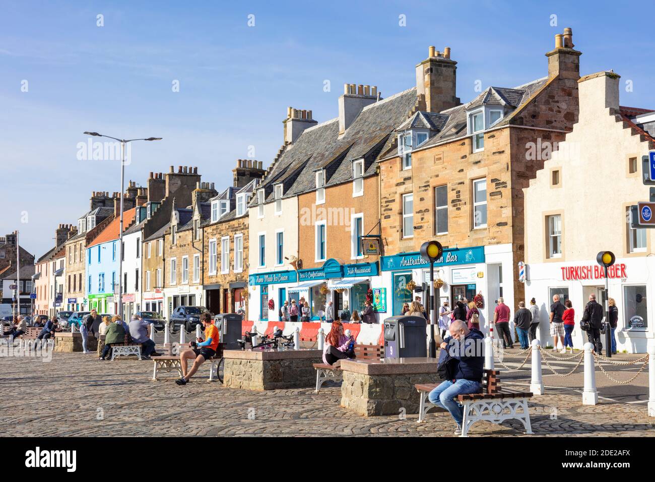 People sat outside the Anstruther Fish bar on the harbour in the scottish coastal port of Anstruther Fife Scotland East Neuk of Fife UK GB Europe Stock Photo