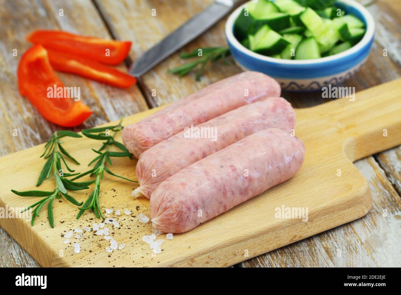 Fresh, uncooked British pork sausages on wooden board Stock Photo