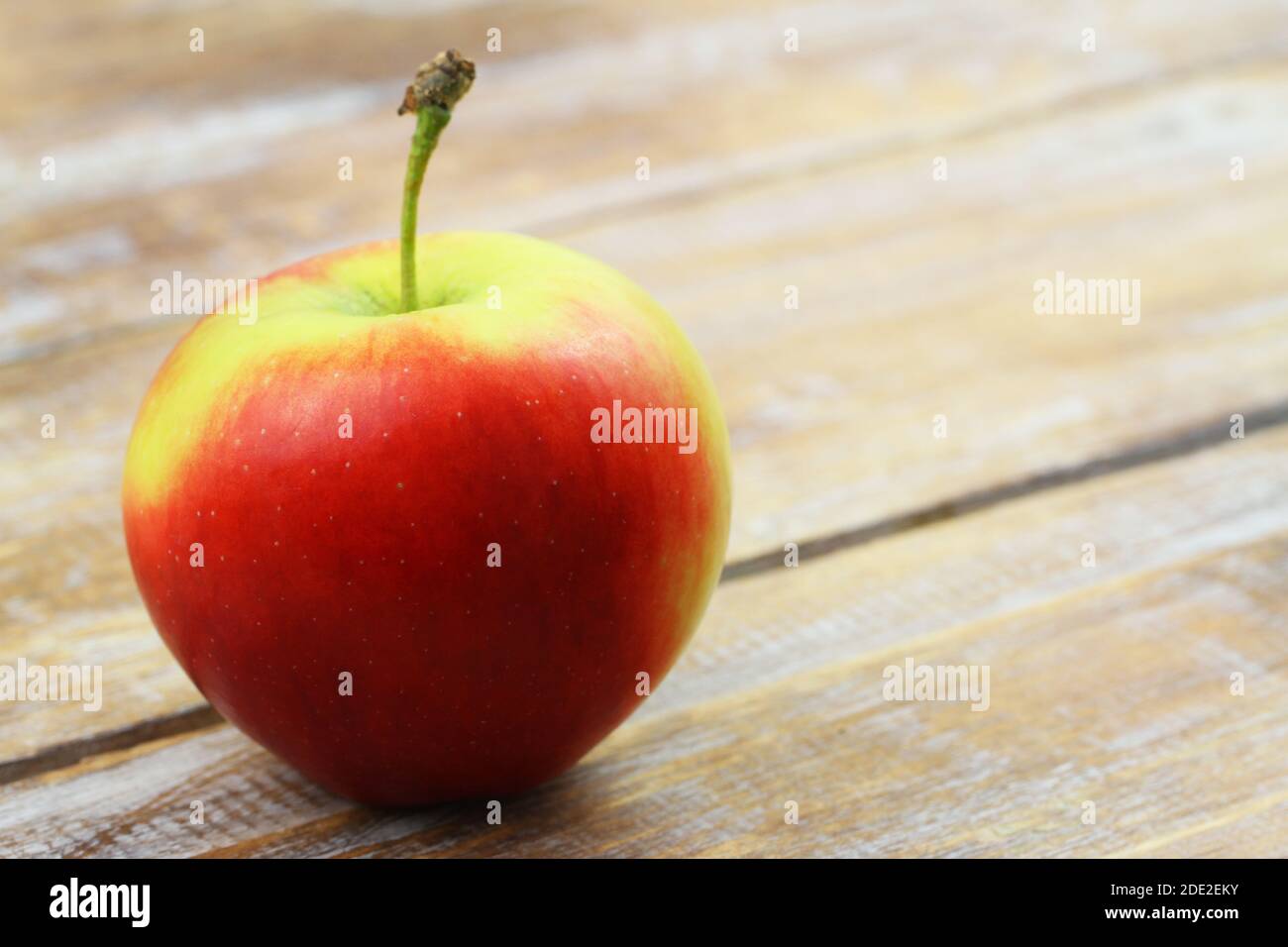 Red and yellow apple on wooden surface with copy space Stock Photo