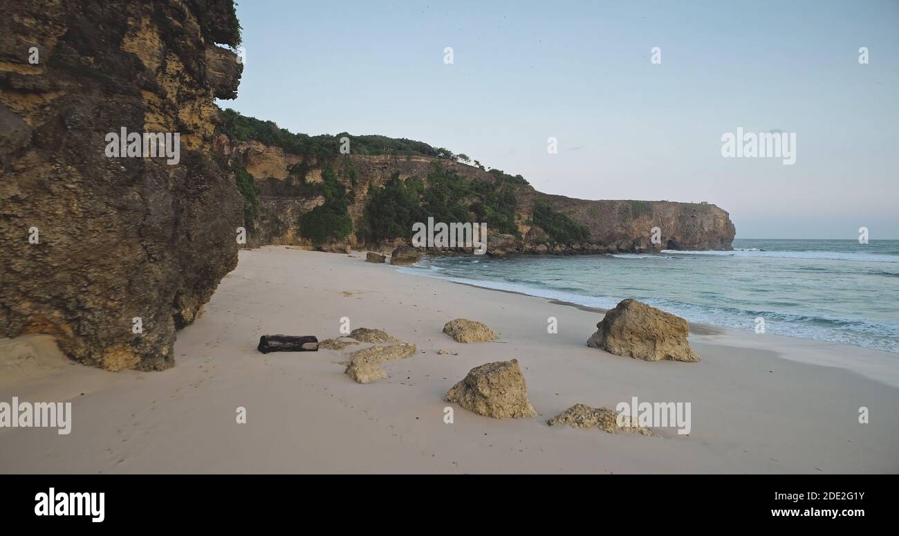 Sand beach at rock ocean coast wavesaerial view. Nobody tropic nature seascape of cliff seashore with boulder at sandy sea bay. Summer tropic landscape of Sumba Island, Indonesia at drone shot Stock Photo