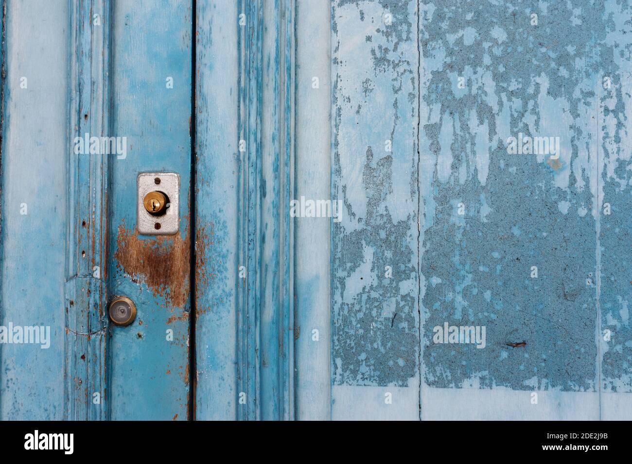 Flaking blue-painted door with lock. Stock Photo