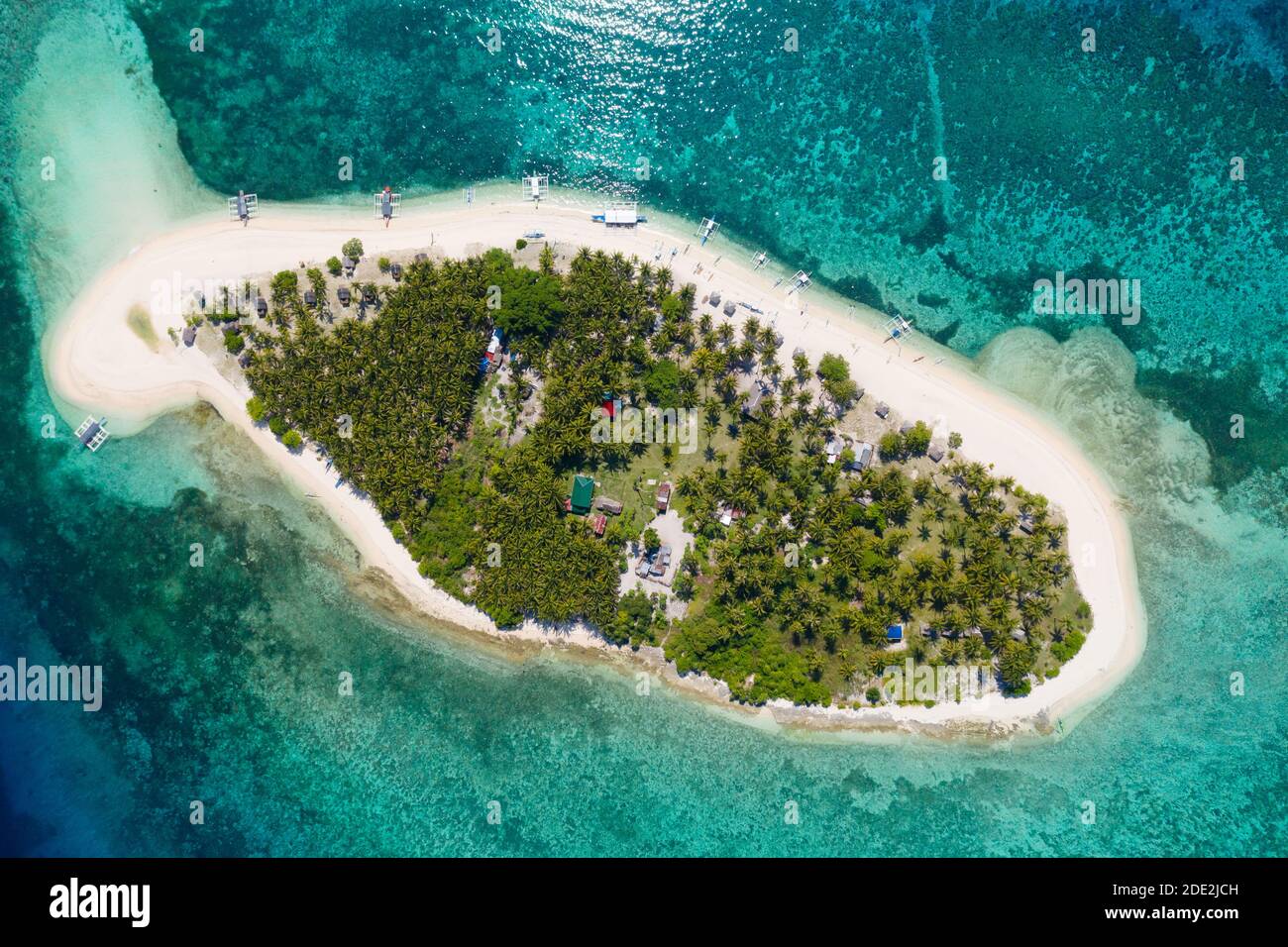 Island with a tropical beach and turquoise lagoons. White sand beach with coconut trees, top view. Digyo Island, Philippines. Stock Photo