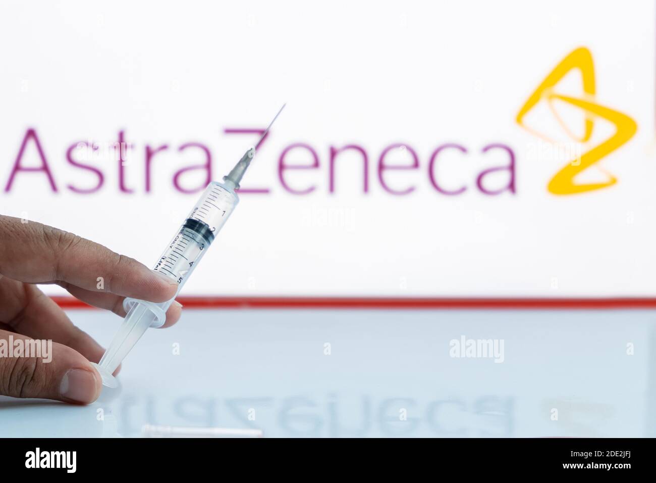 Kathmandu, Nepal - November 28 2020: Man holds empty syringe against AstraZeneca Logo. Stock Photo