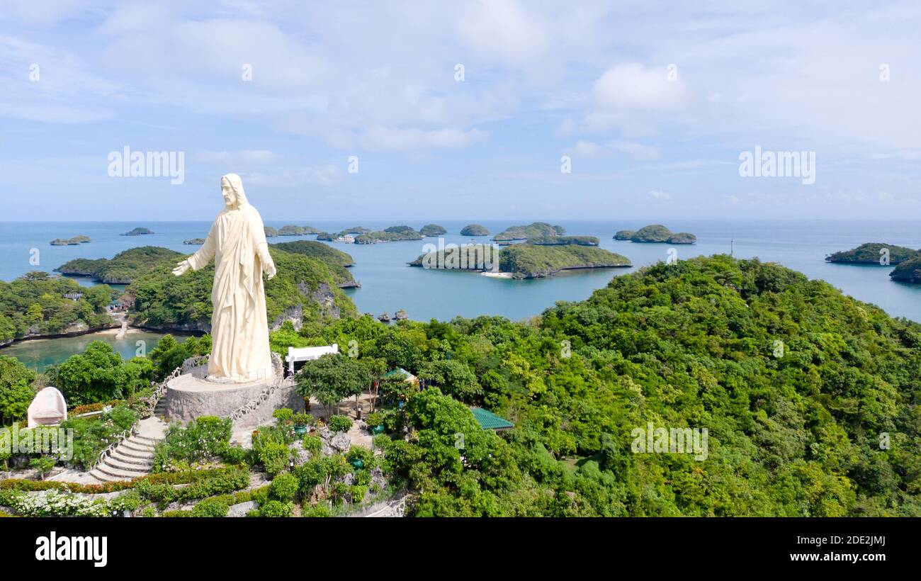 Statue of Jesus Christ on Pilgrimage island in Hundred Islands National Park, Pangasinan, Philippines. Aerial view of group of small islands with beac Stock Photo