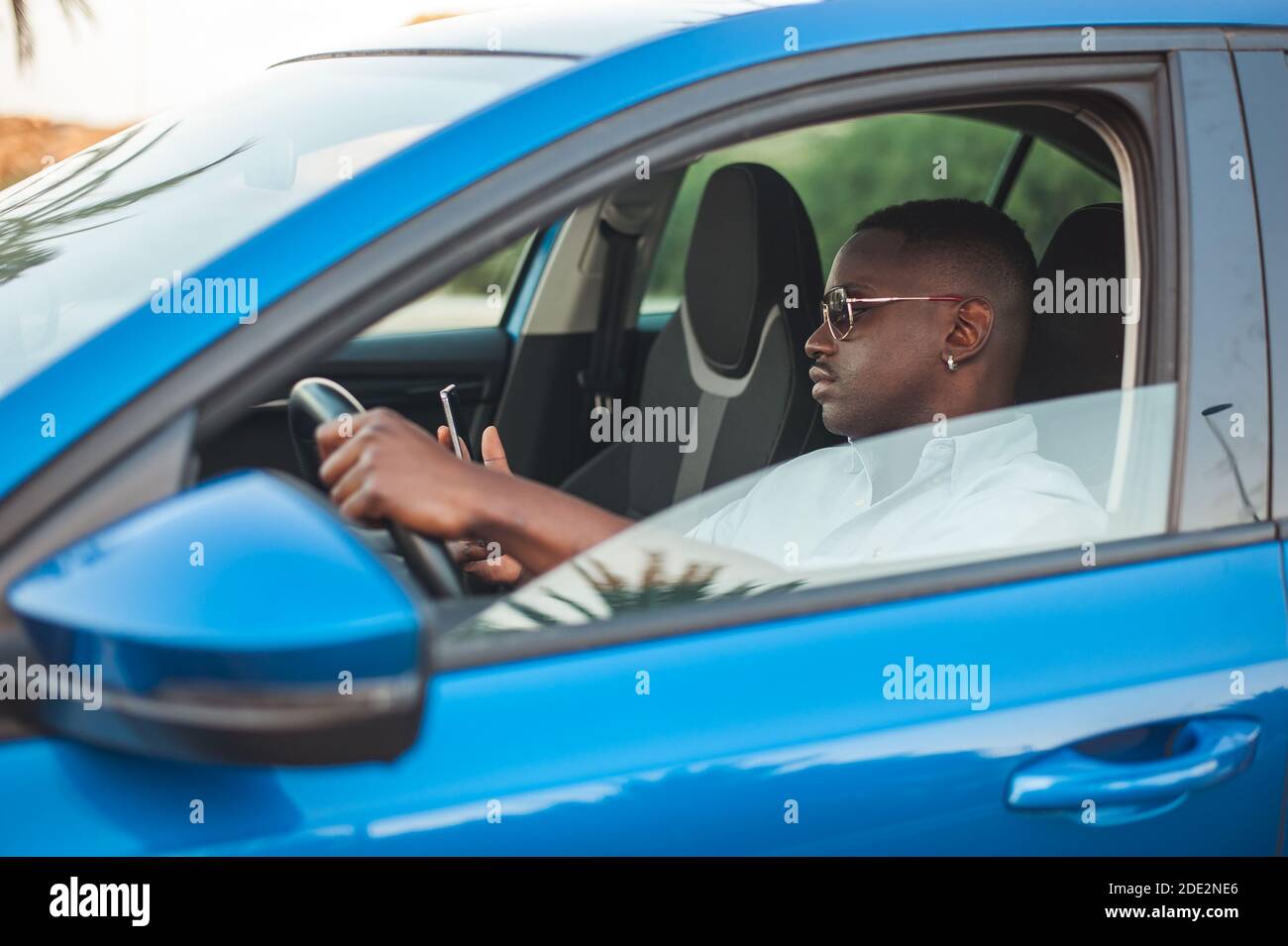 Black entrepreneur using his phone while driving Stock Photo