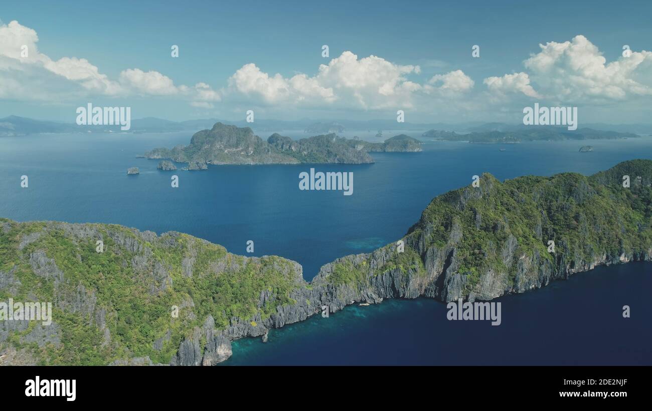 Mountainous tropical islands at ocean bay aerial rise up view. Mountain ranges at tropic isle of El Nido, Philippines. Nobody nature seascape with serene blue water. Cinematic soft light drone shot Stock Photo