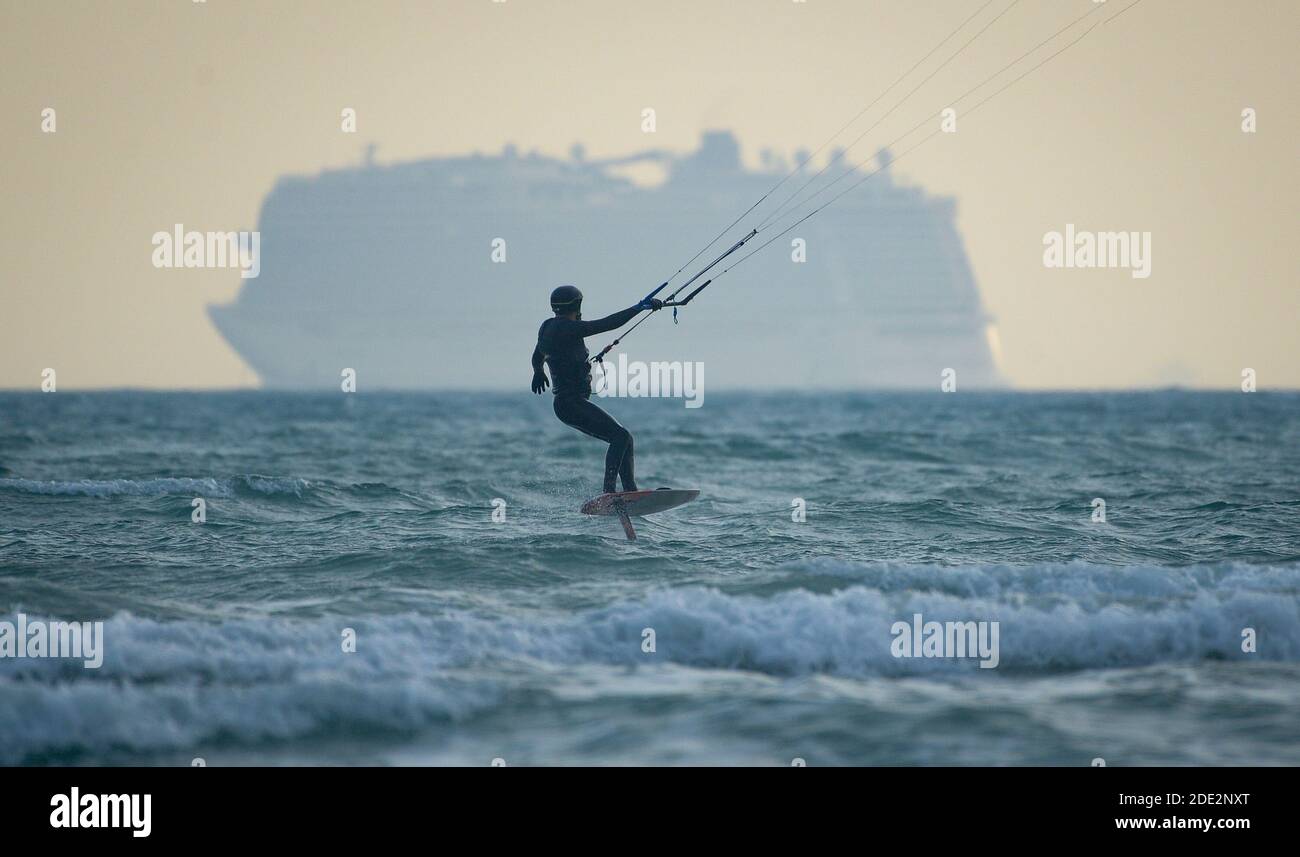Weymouth, Dorset, UK. 28th Nov, 2020. UK Weather: A hydrofoil kite surfer with anchored cruise ships. Credit: Dorset Media Service/Alamy Live News Stock Photo