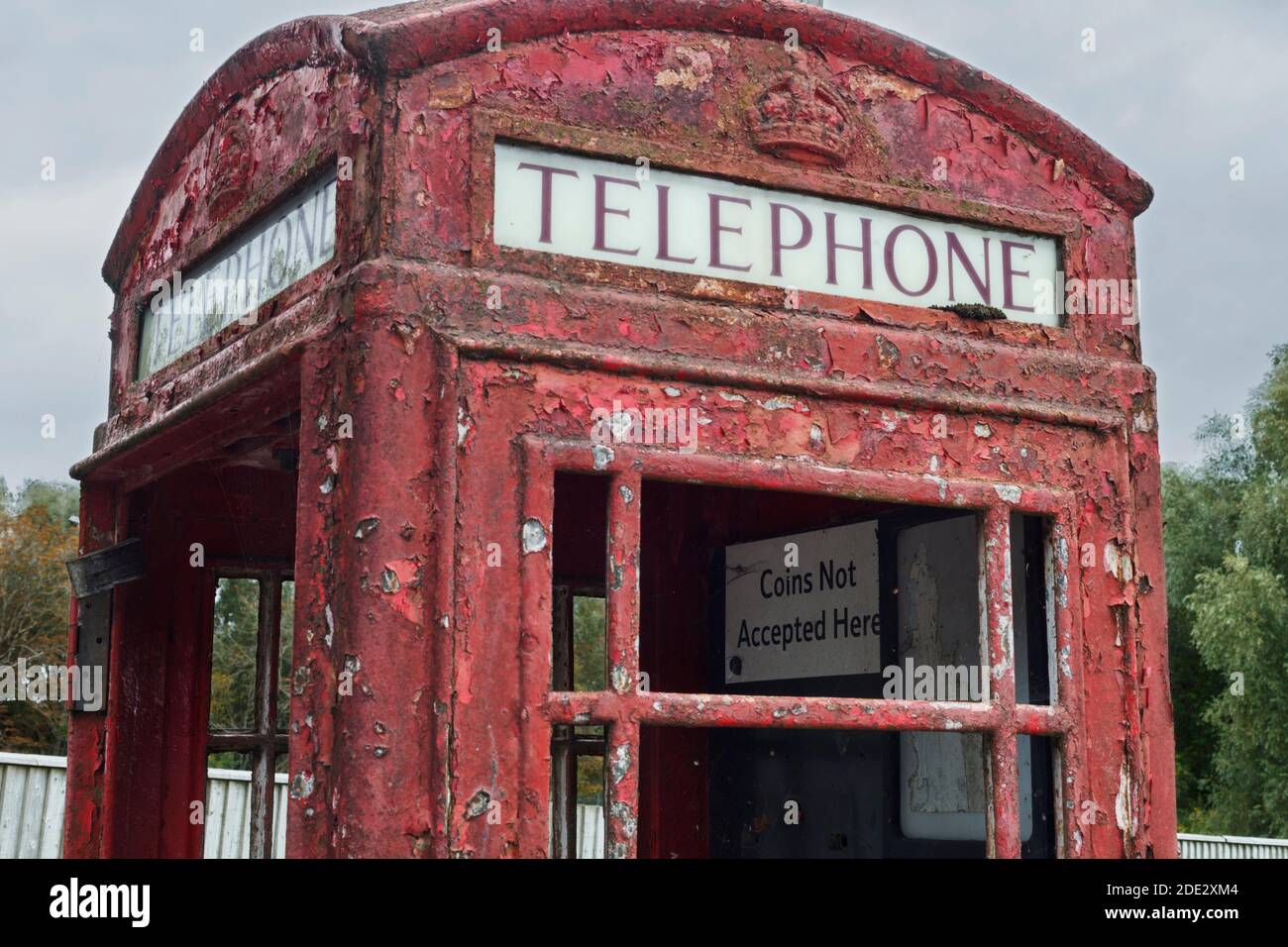 Abandoned old red phone box with broken smashed glass and peeling red paint Stock Photo