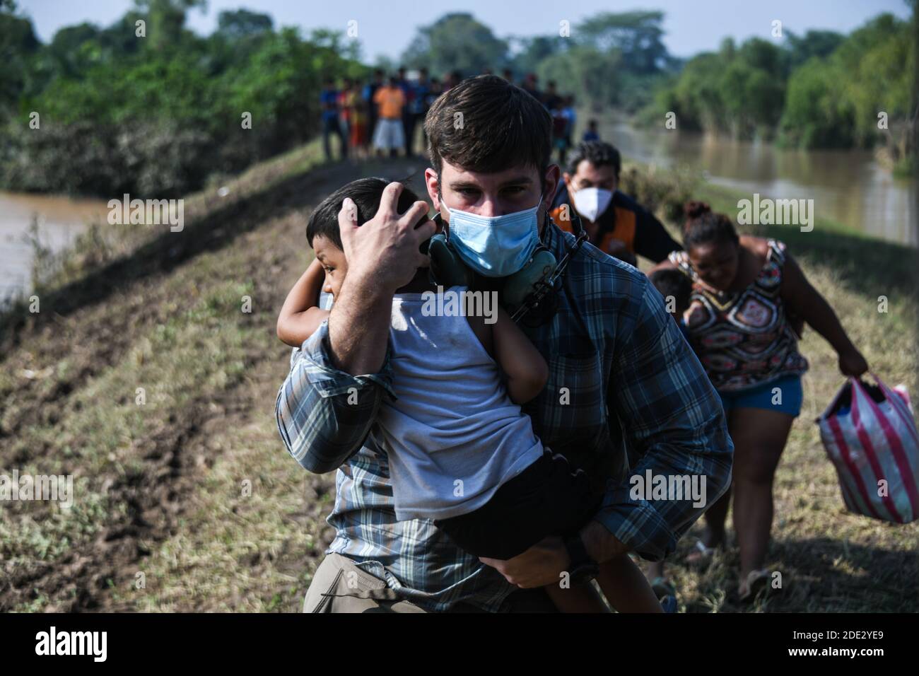 A U.S. Army soldier carries a Honduran child to a HH-60 Black Hawk helicopter for evacuation following a massive hurricane November 10, 2020 in Choloma, Honduras. Hurricane Eta swept through Central America destroying large sections of the coast and flooding roads. Stock Photo