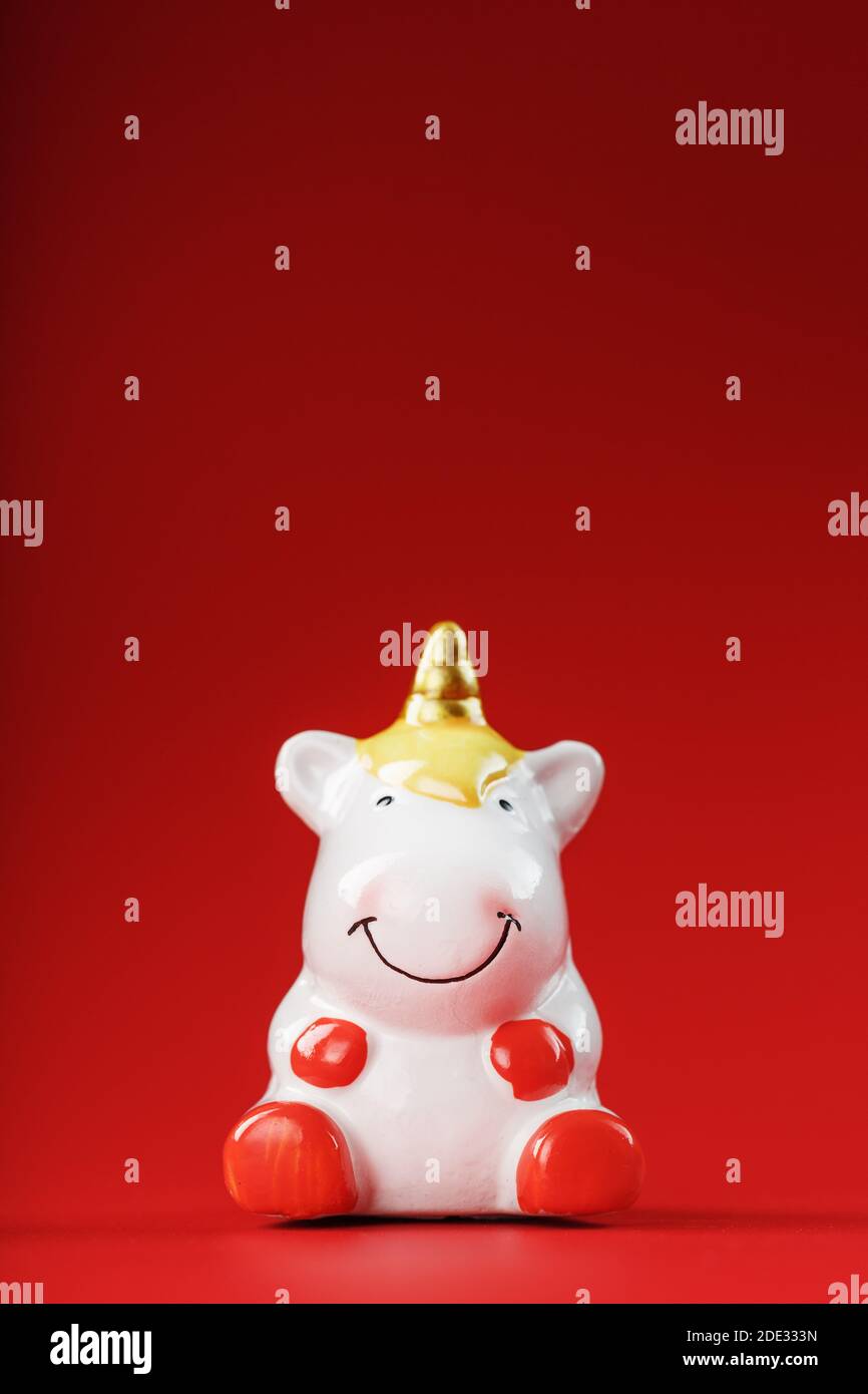 Unicorn figurine on a red background with free space. Symbol of good