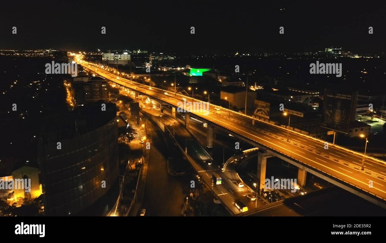 Closeup night traffic highway with driving cars, vans, trucks aerial view. Urban cityscape of Philippines metropolis of Manila close up. Modern buildings with bright illuminated road on bridge Stock Photo