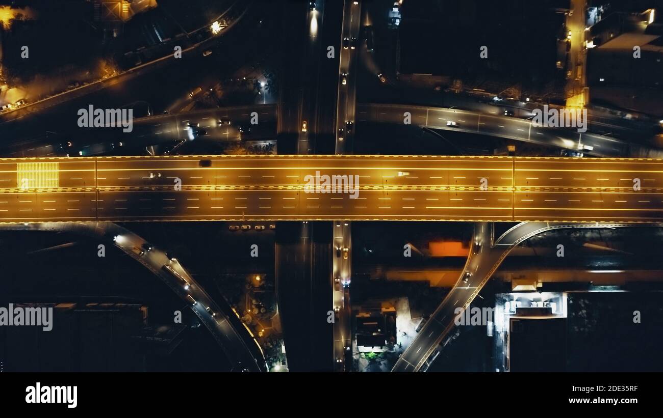 Top down night traffic highway bridge at Philippine metropolis city Manila. Aerial view of cars, trucks drive at urban business centre of Filipino capital. Illuminated town lights at road with vehicle Stock Photo