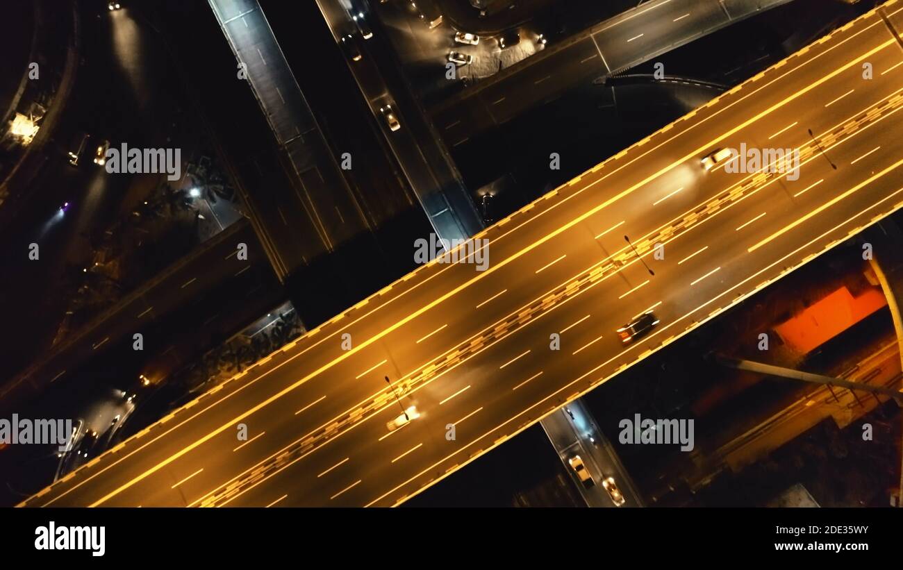 Closeup aerial top down of cars ride at night traffic road. Philippine cityscape with vehicles at highway. Urban transportation on illuminated freeway. Twilight roadway view at neon lights Manila city Stock Photo