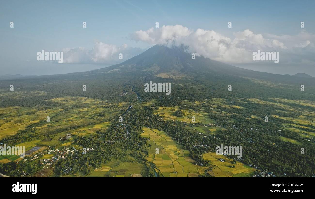 Mayon volcano erupts at Philippines countryside aerial. Tropic green forest plants and grasses at picturesque nobody nature landscape. Legazpi town at mountain hillside valley at cinematic drone shot Stock Photo