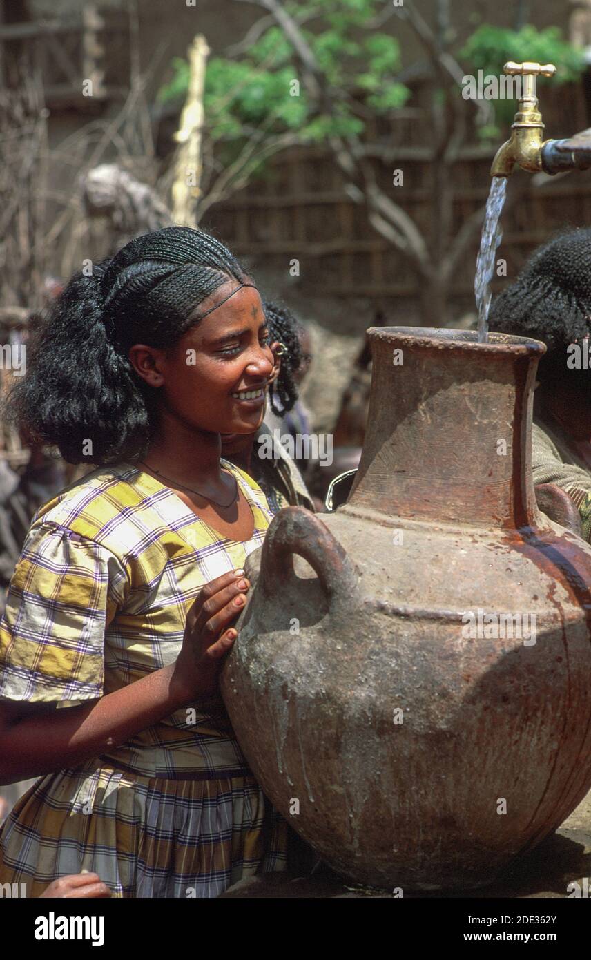 Young woman collecting water in a large urn at the community water taps. Addis Ababa, Ethiopia Stock Photo
