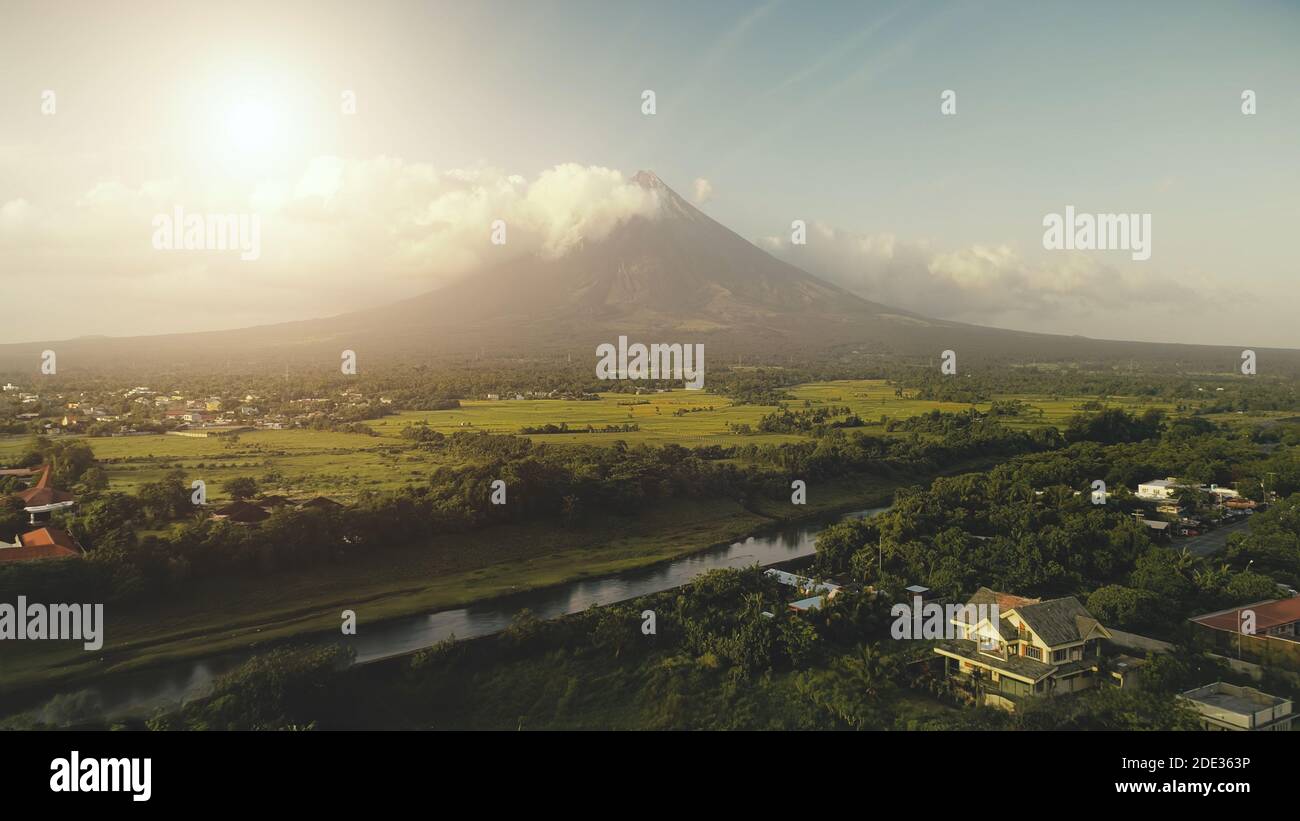 Sun shine over Mayon volcano eruption aerial. River at green grass hillside. Tropic forest at Legazpi attraction. Philippines countryside at nobody nature landscape. Cinematic soft light shot Stock Photo