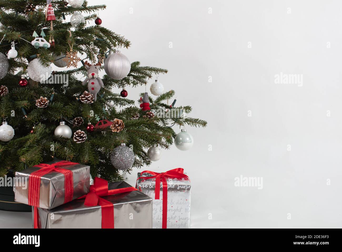 Christmas tree with three presents under it. Silver-white-red colored gift boxes Stock Photo