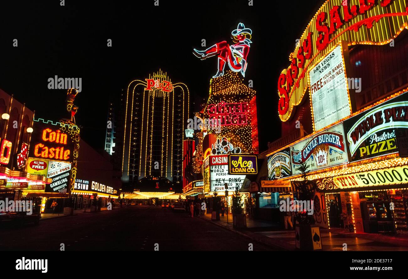Neon and other colorful lights made these outdoor signs for casinos and hotels stand out at night and during the day along Fremont Street, the original downtown center for gambling and good times in Las Vegas, Nevada, USA. Easily recognized in the neon display is a cowgirl nicknamed Vegas Vickie. Since this historical photograph was taken in 1983, Fremont St. has been covered with a canopy that is the world's longest video screen and presents an overhead sound-and-light show to visitors in the pedestrian-only street below. The glowing lights of neon signs first appeared in Las Vegas in 1929. Stock Photo