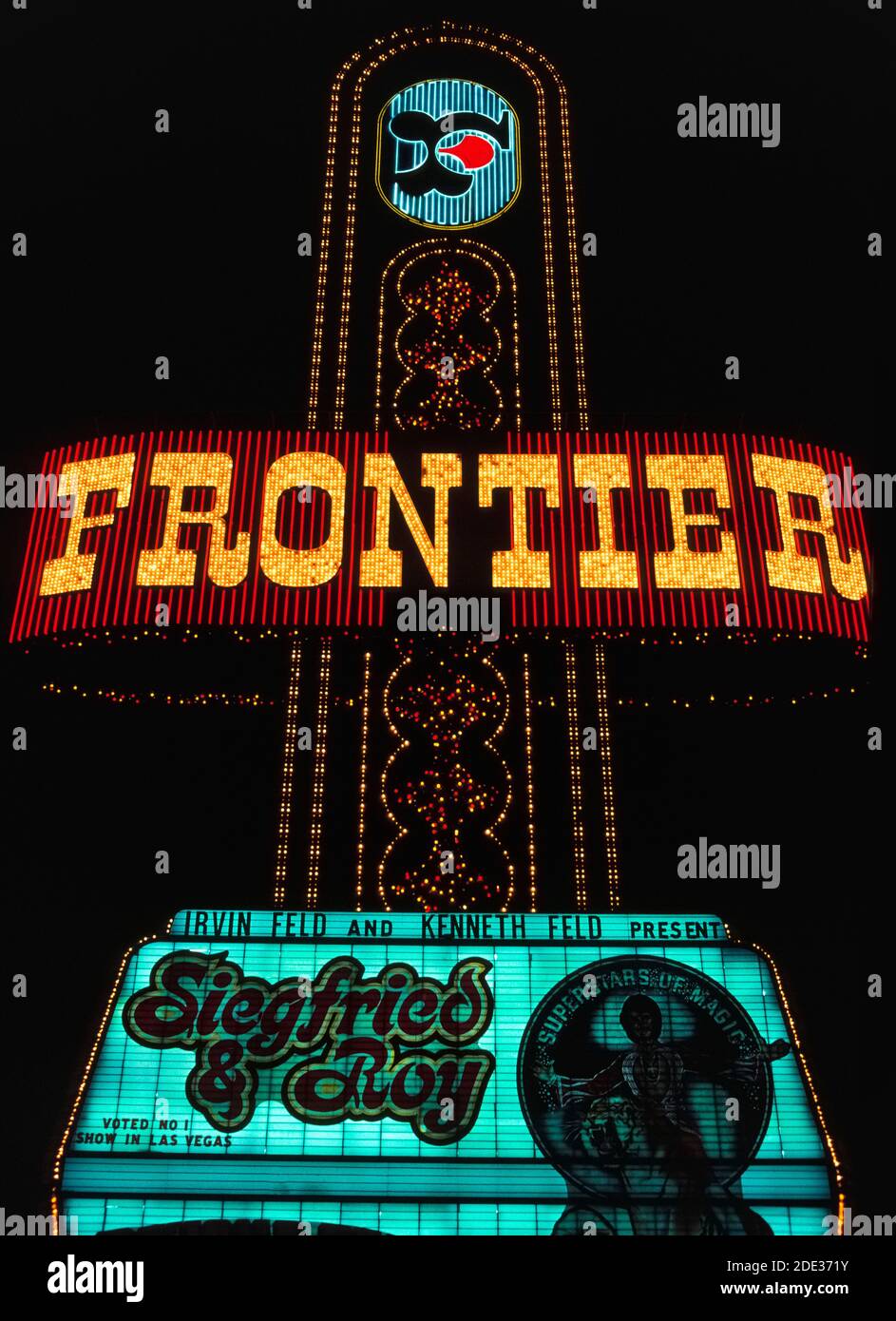 Neon and other colorful lights made this outdoor sign for the Frontier Hotel and Casino stand out at night along Las Vegas Boulevard, better known as the Strip, a roadway lined with spectacular resort hotels and casinos just south of the city limits of Las Vegas, Nevada, USA. The Stardust opened in 1942 and operated for 65 years in that notorious desert destination well-known for its gambling and good times. This historical photograph was taken in 1983 before the Frontier was demolished in 2007. The sign advertises the star entertainers in the hotel's showroom, magicians Siegfried and Roy. Stock Photo